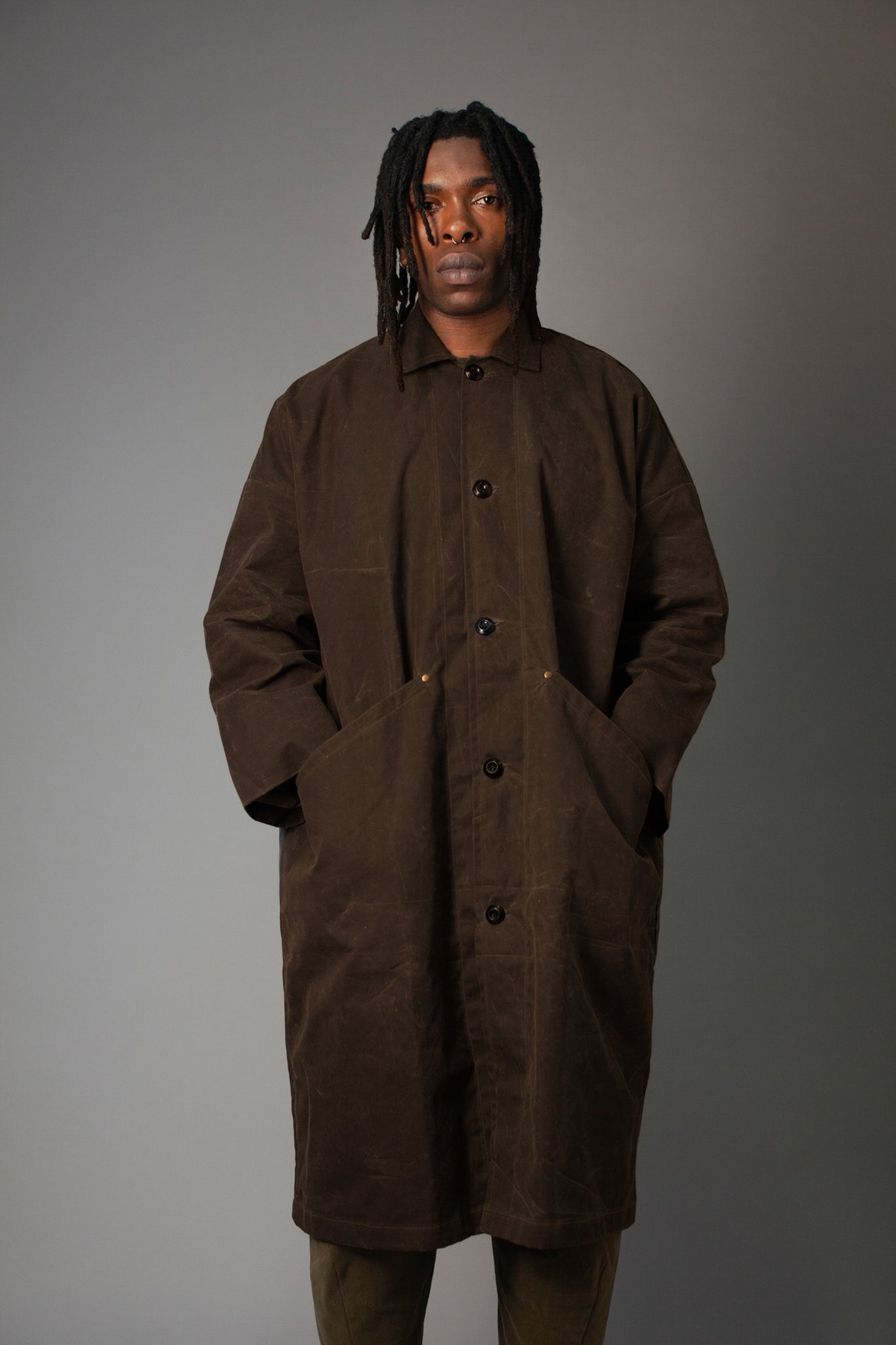 Man wearing a brown coat against a gray background