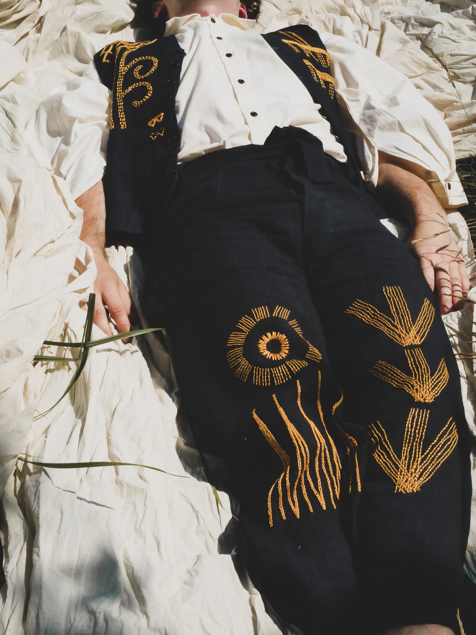 Person wearing a navy outfit with yellow hand embroidery against a natural background