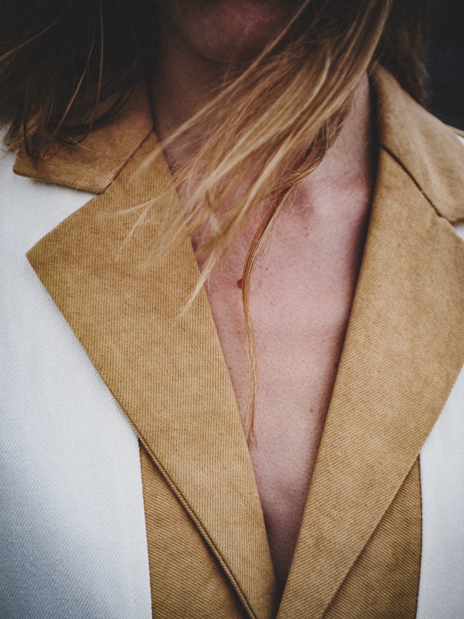 Close-up of a person wearing a mustard coat with a blurred background