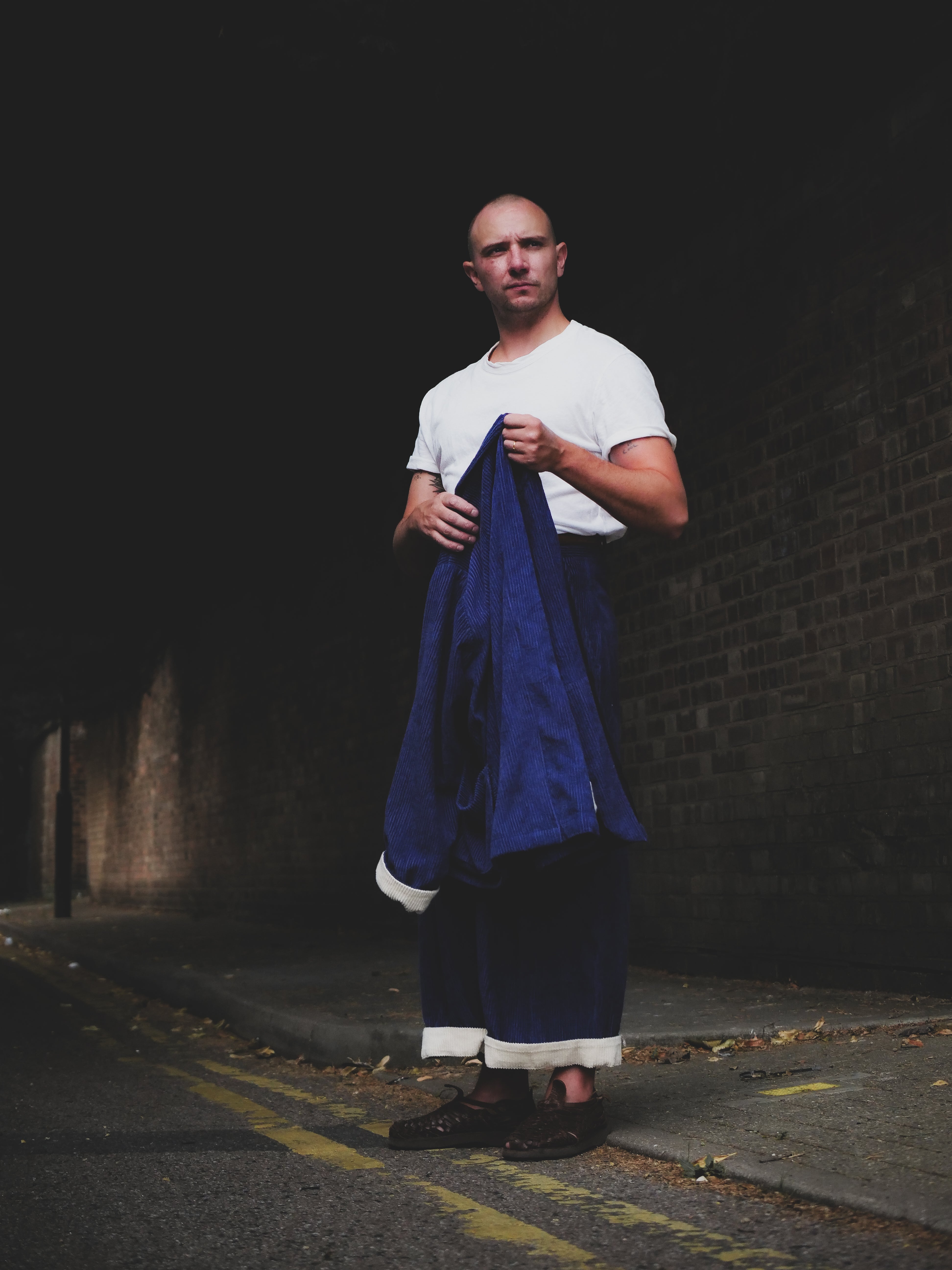 Man holding a blue garment against a dark background