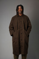 Man wearing a brown coat against a gray background