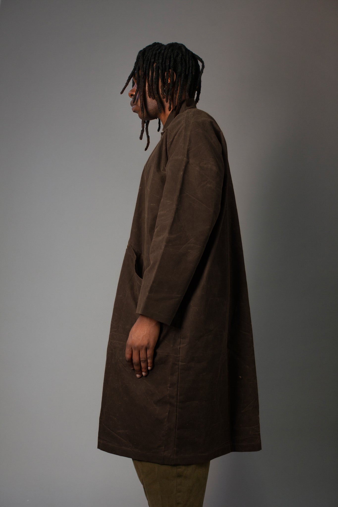 Person wearing a brown coat against a gray background