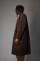 Person wearing a brown coat against a gray background