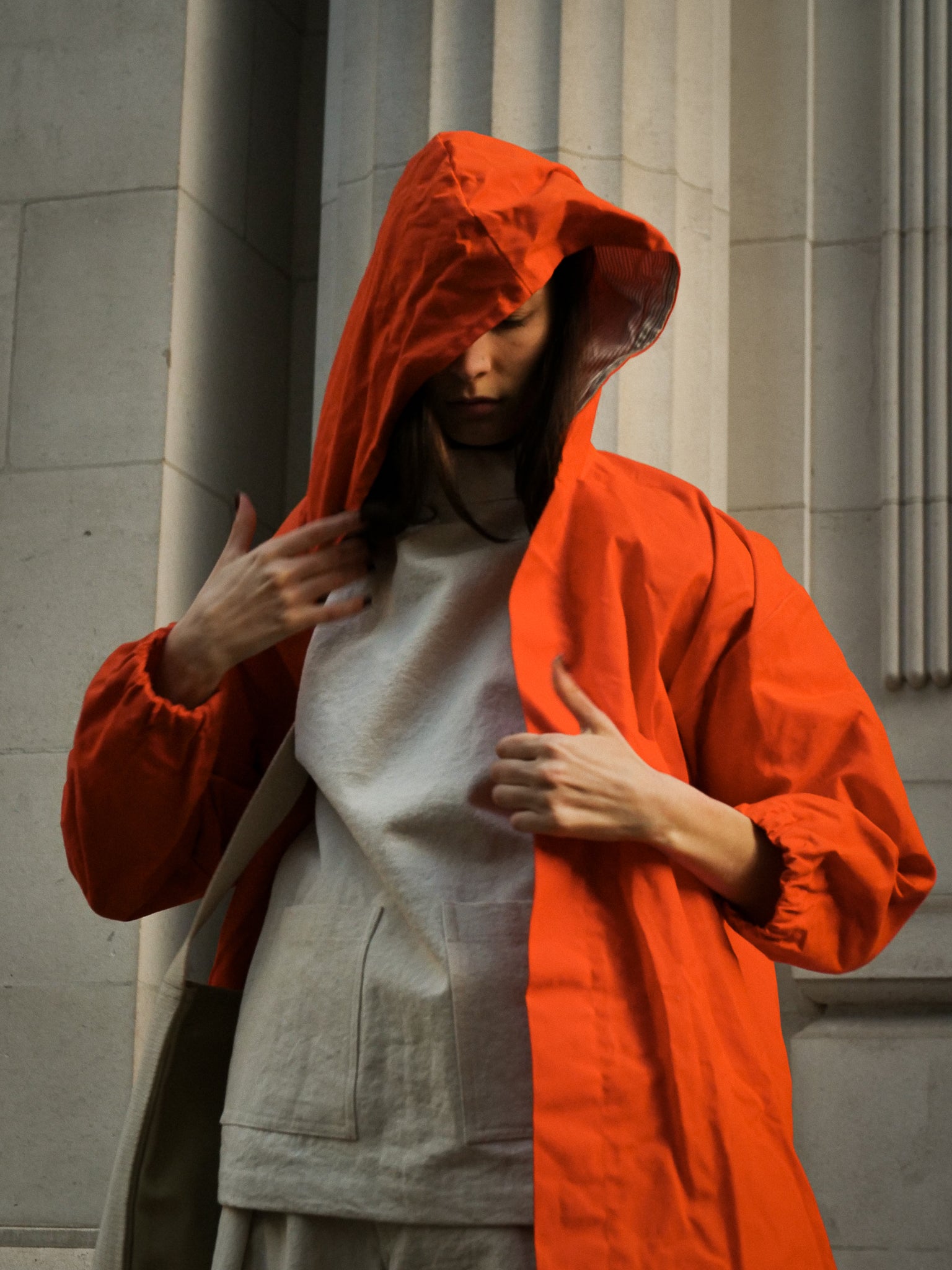 Person wearing an orange hooded garment against a neutral background