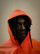 Person wearing an orange hooded jacket against a plain background
