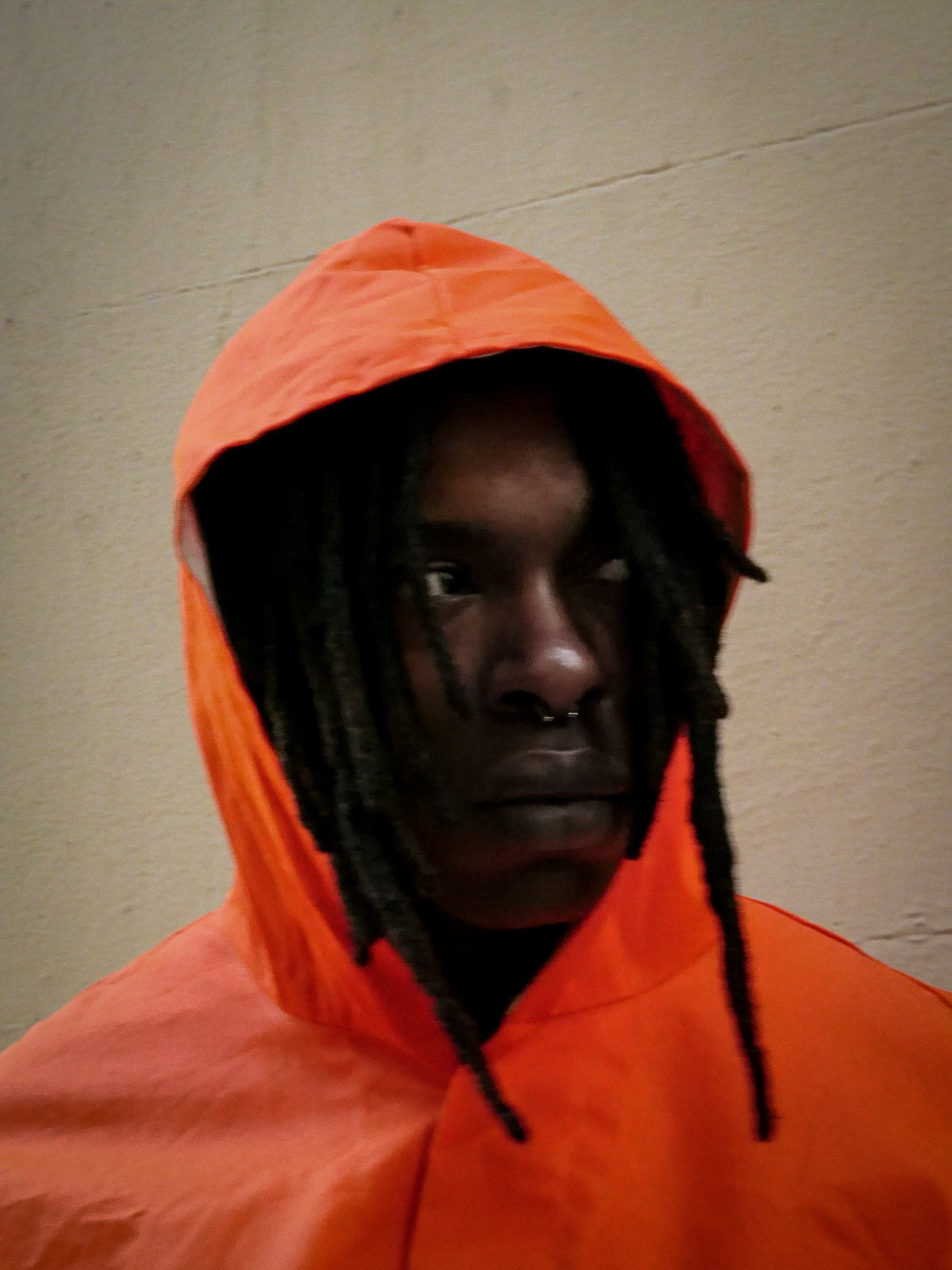 Person wearing an orange hooded jacket against a plain background