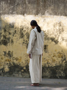 Person wearing a beige outfit standing against a textured wall.