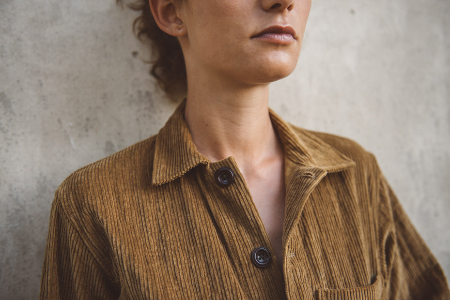 Person wearing a brown corduroy shirt against a gray background