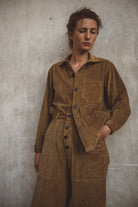 Woman wearing a brown corduroy outfit against a plain background