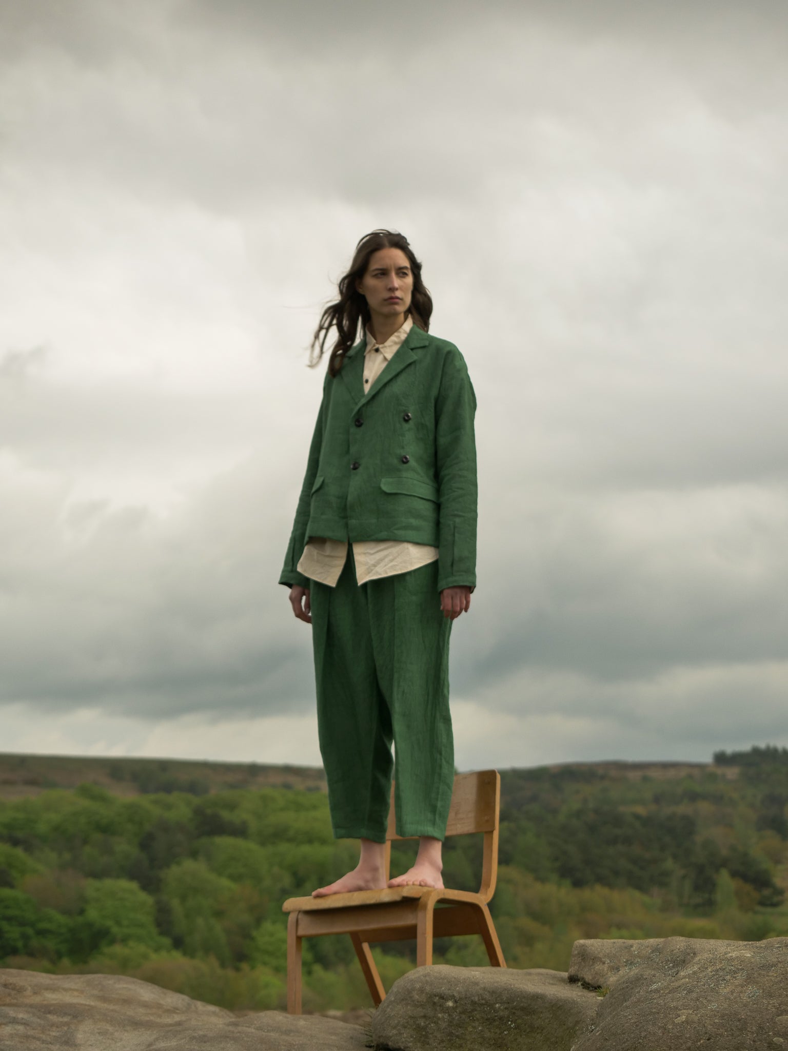 Person wearing a green suit standing on a chair with a scenic background
