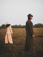 Two people standing in a field with trees in the background