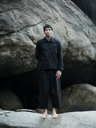 Person wearing a dark outfit standing in front of large rocks