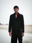 Man wearing a black coat and pants standing in a snowy landscape.