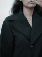 Person wearing a black coat with a blurred background