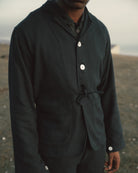 Person wearing a black jacket with buttons in an outdoor setting