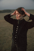 Woman in a black jacket standing in a field with a blurred background