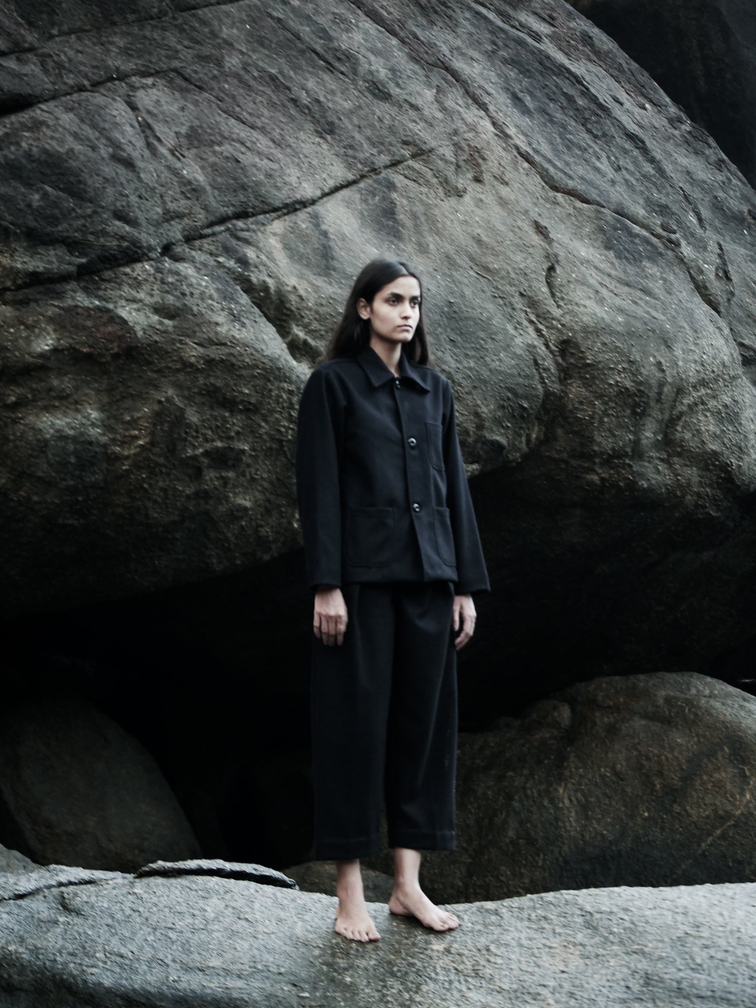 Person wearing a black outfit standing in front of large rocks