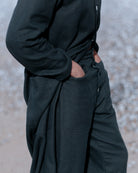 Person wearing a black coat and pants against a blurred background