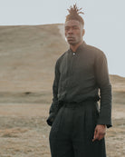 Man in dark clothing standing in a desert landscape