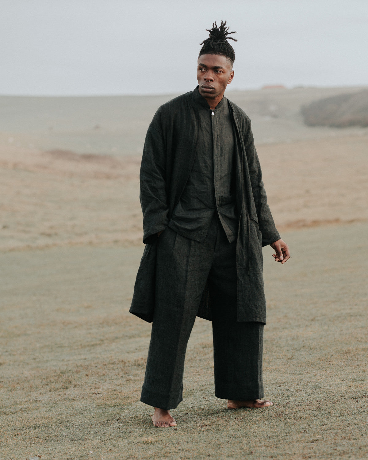 Man in dark clothing standing in a barren landscape
