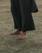 Person wearing black wide legged trousers standing on a grassy field