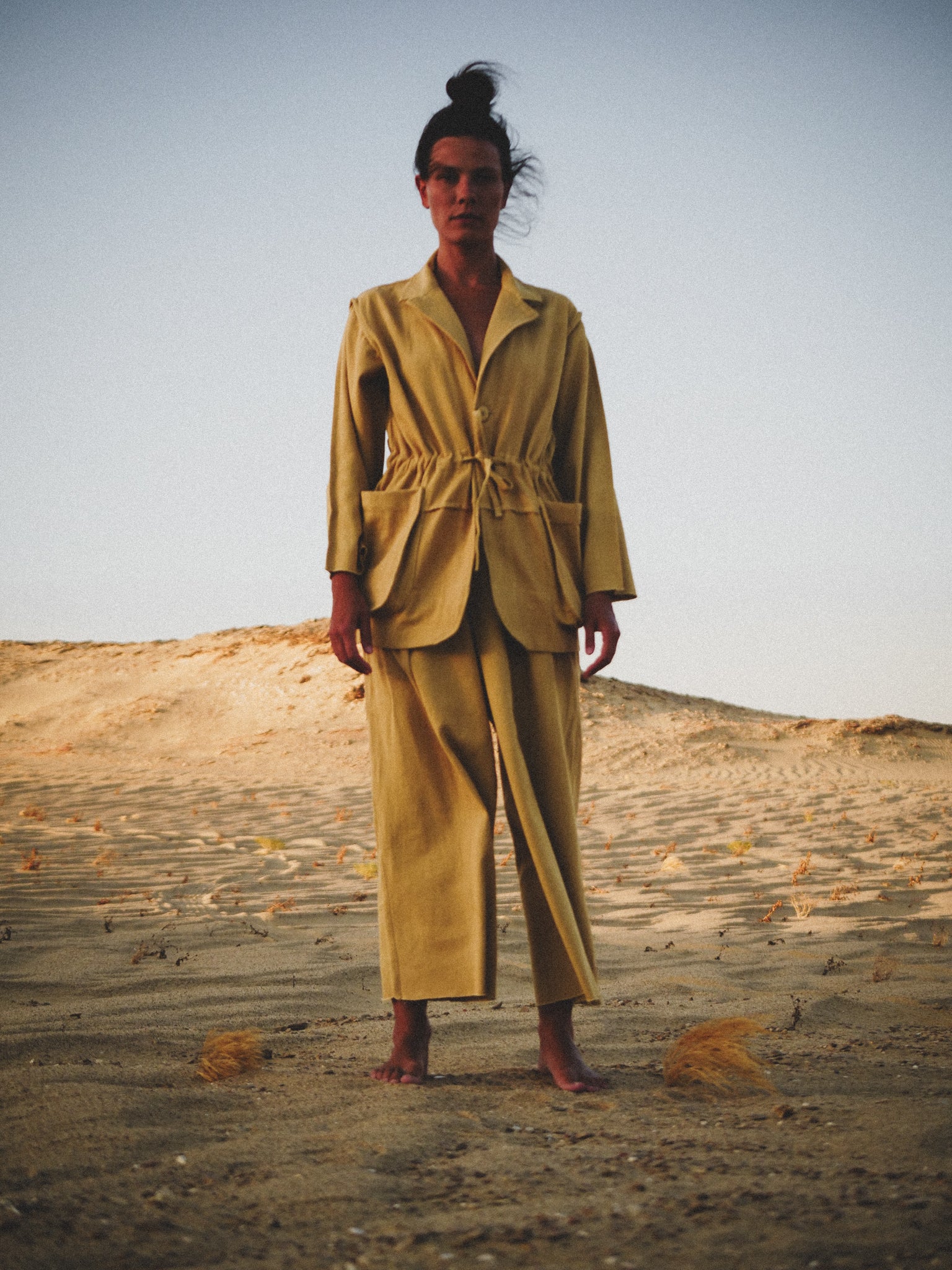 Person wearing a mustard suit standing in a desert landscape