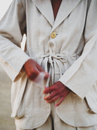 Person wearing a white suit with red gloves on a neutral background