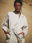 Person wearing a white jacket against a beige background