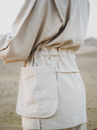 White outfit with a focus on the pants and jacket against a blurred background