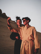 Two people in suits standing in a desert-like setting with a clear sky.