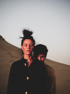 Two people standing close together with a desert landscape in the background