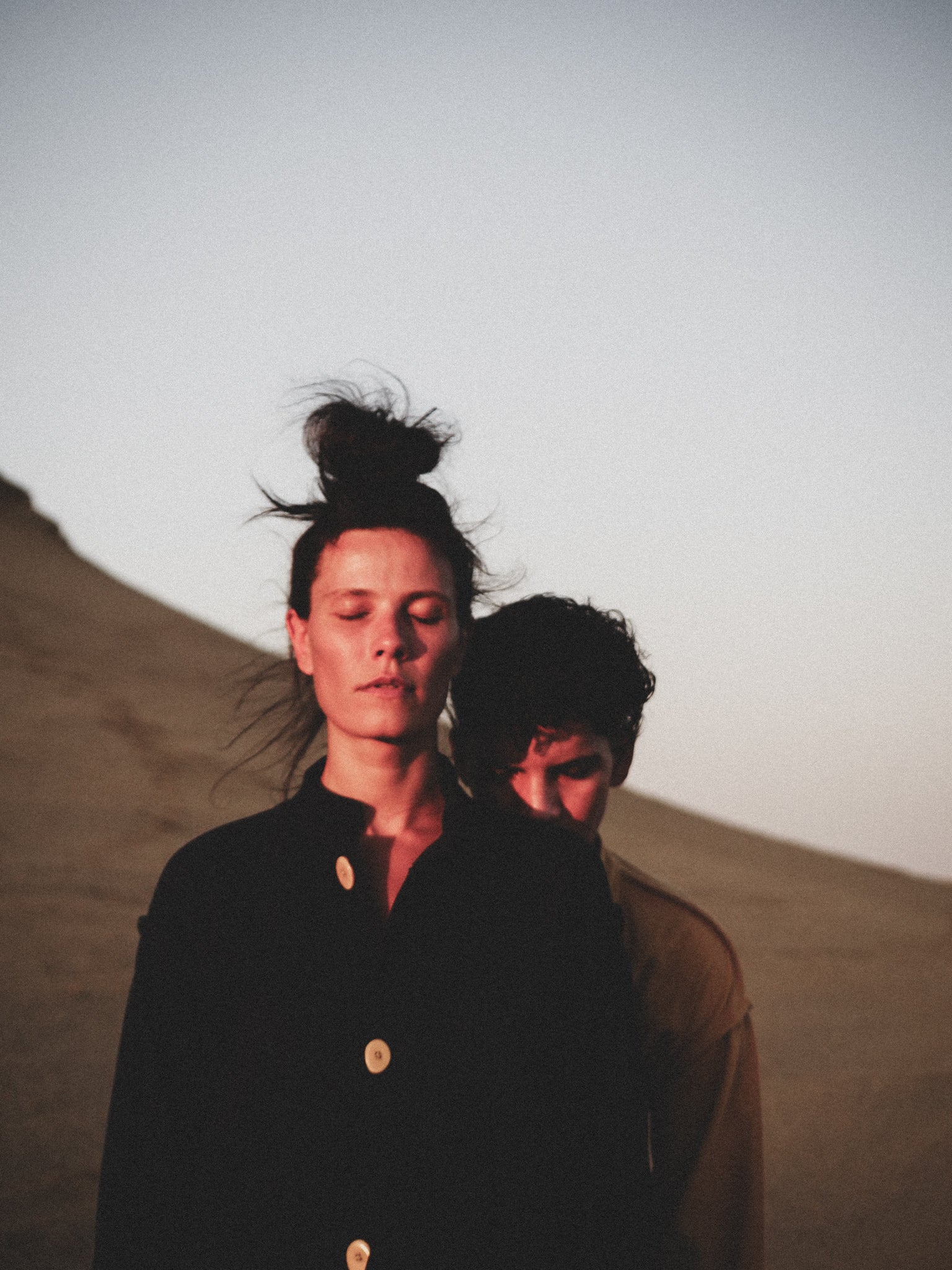 Two people standing close together with a desert landscape in the background