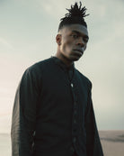 Man with styled hair wearing a dark shirt against a neutral background