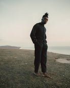 Man in dark clothing standing on a grassy field with a distant landscape.