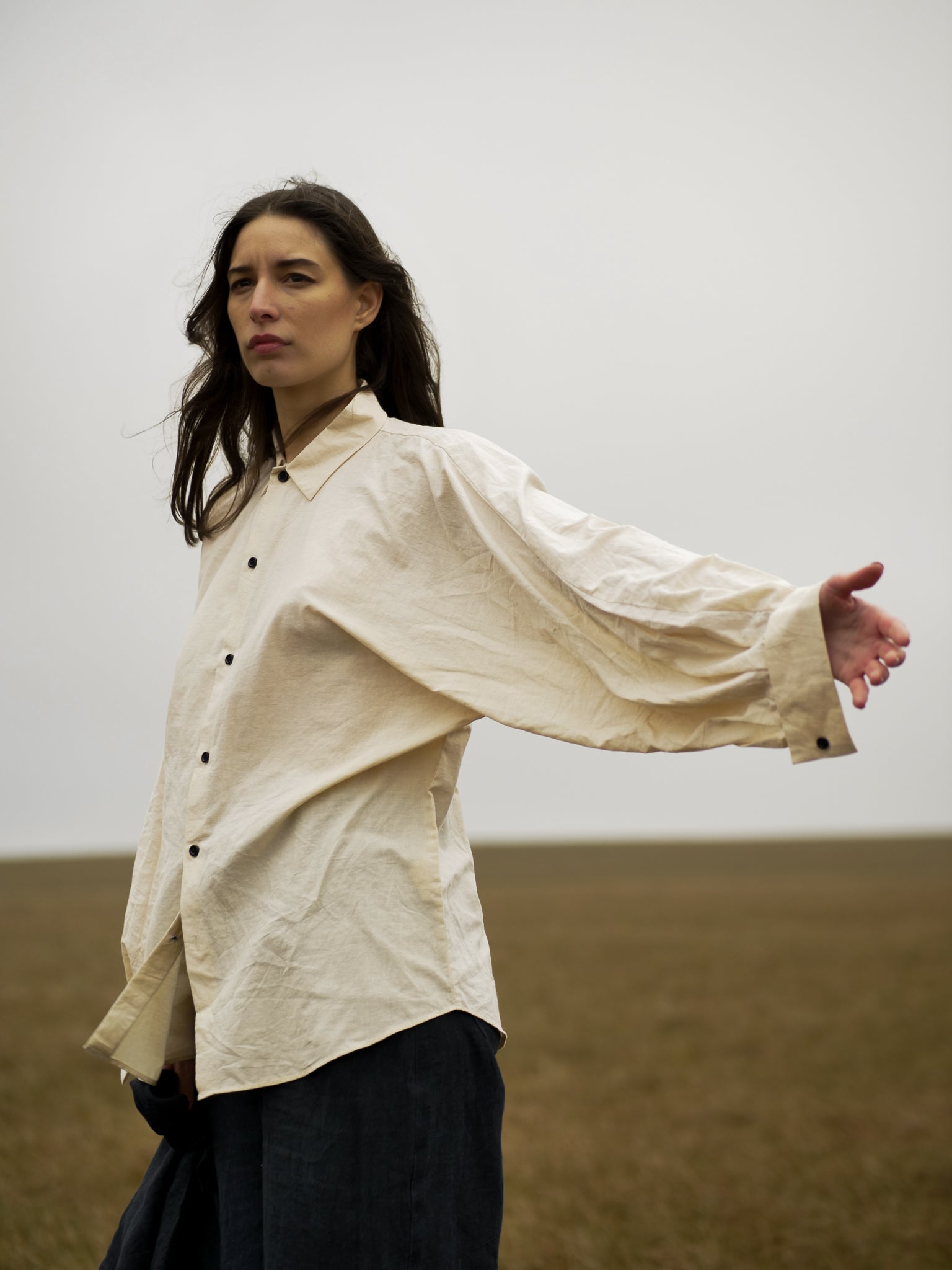 Woman wearing a light-colored shirt with wide sleeves in a desert landscape