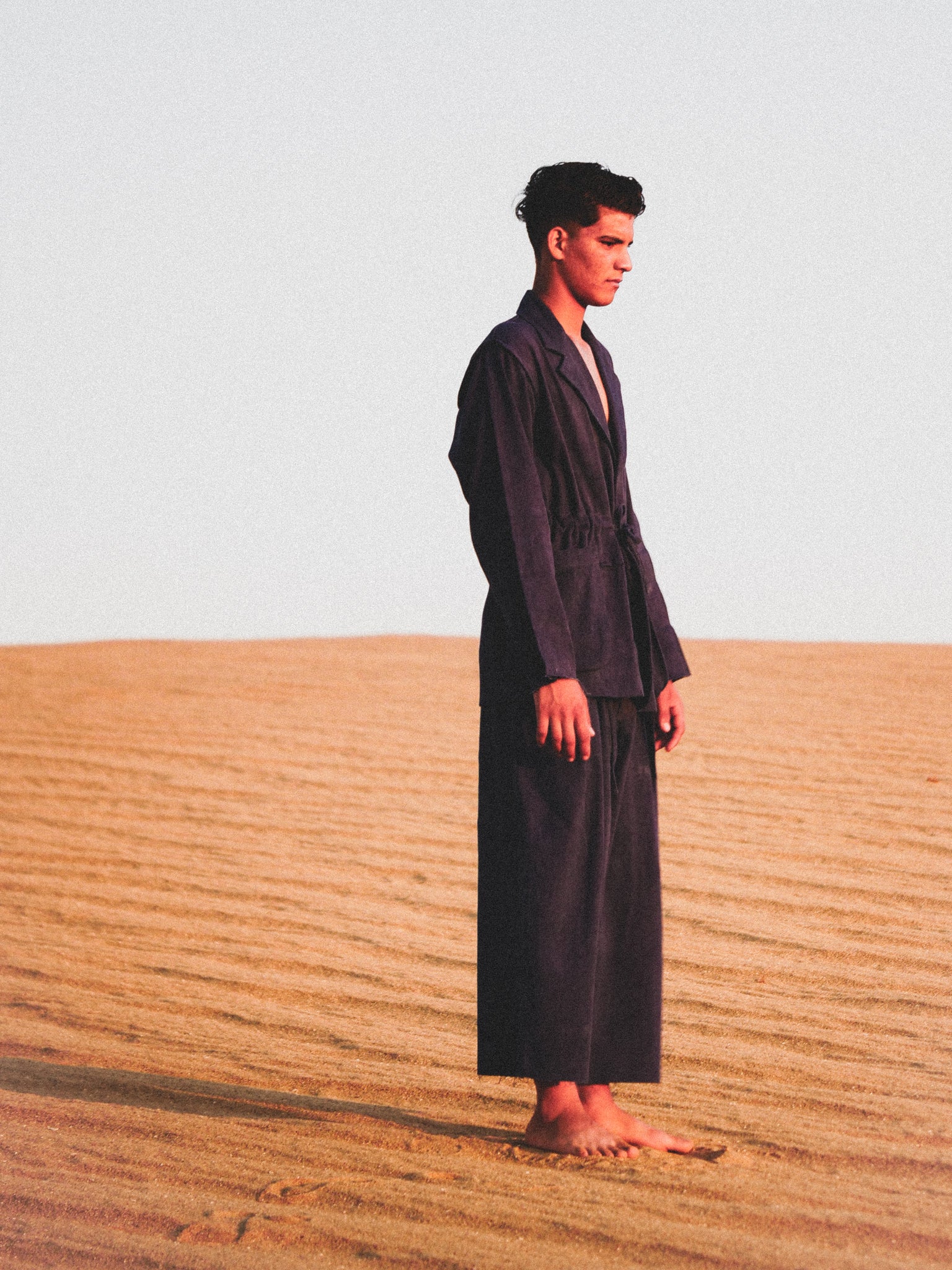 Man in a navy suit standing in a desert landscape