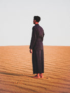 Person in a navy suit standing in a desert landscape