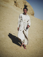 Person in a white suit standing in a desert landscape
