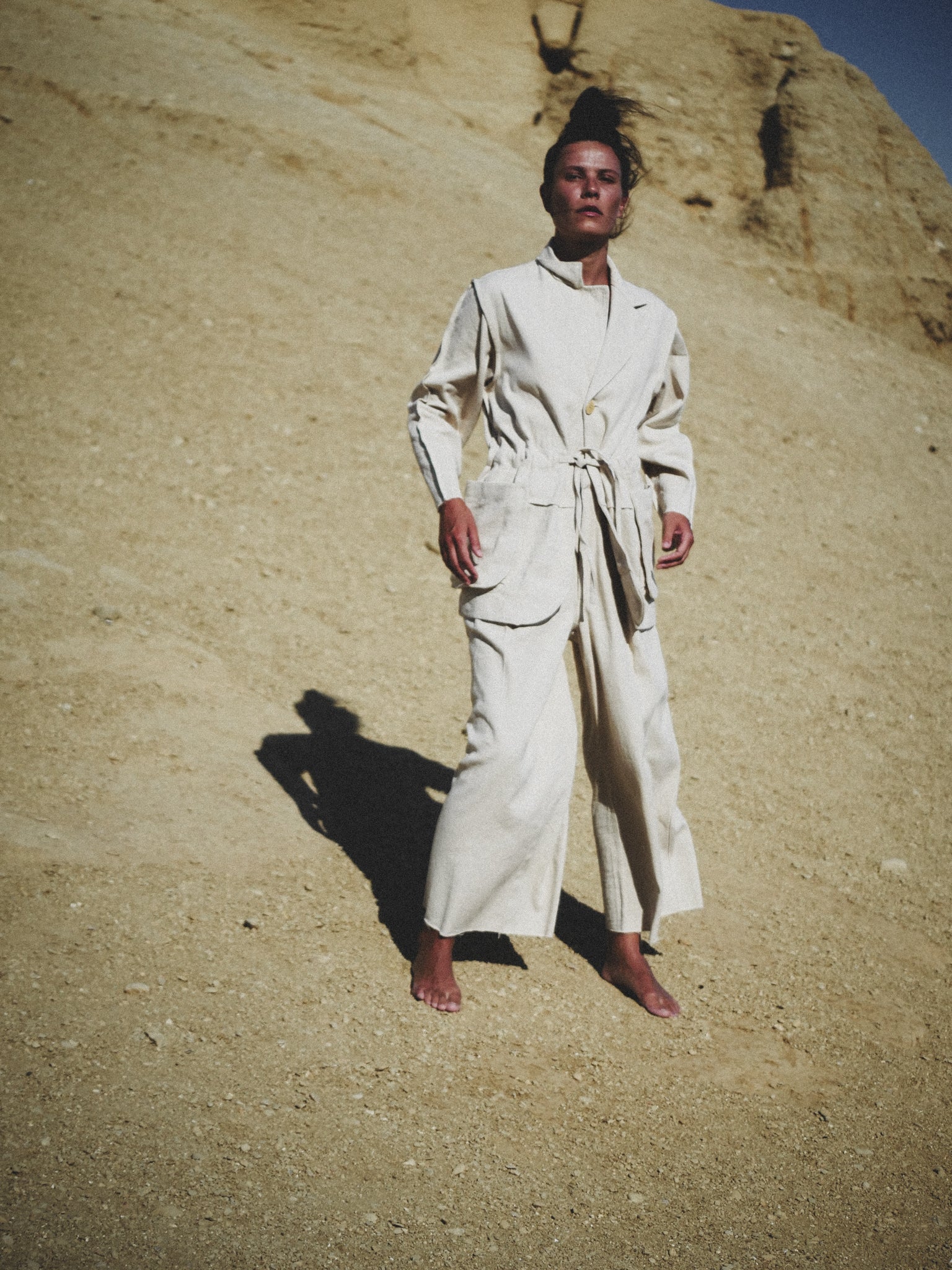 Person wearing a white outfit standing in a desert landscape