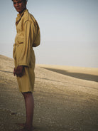 Person wearing a mustard outfit standing in a desert landscape