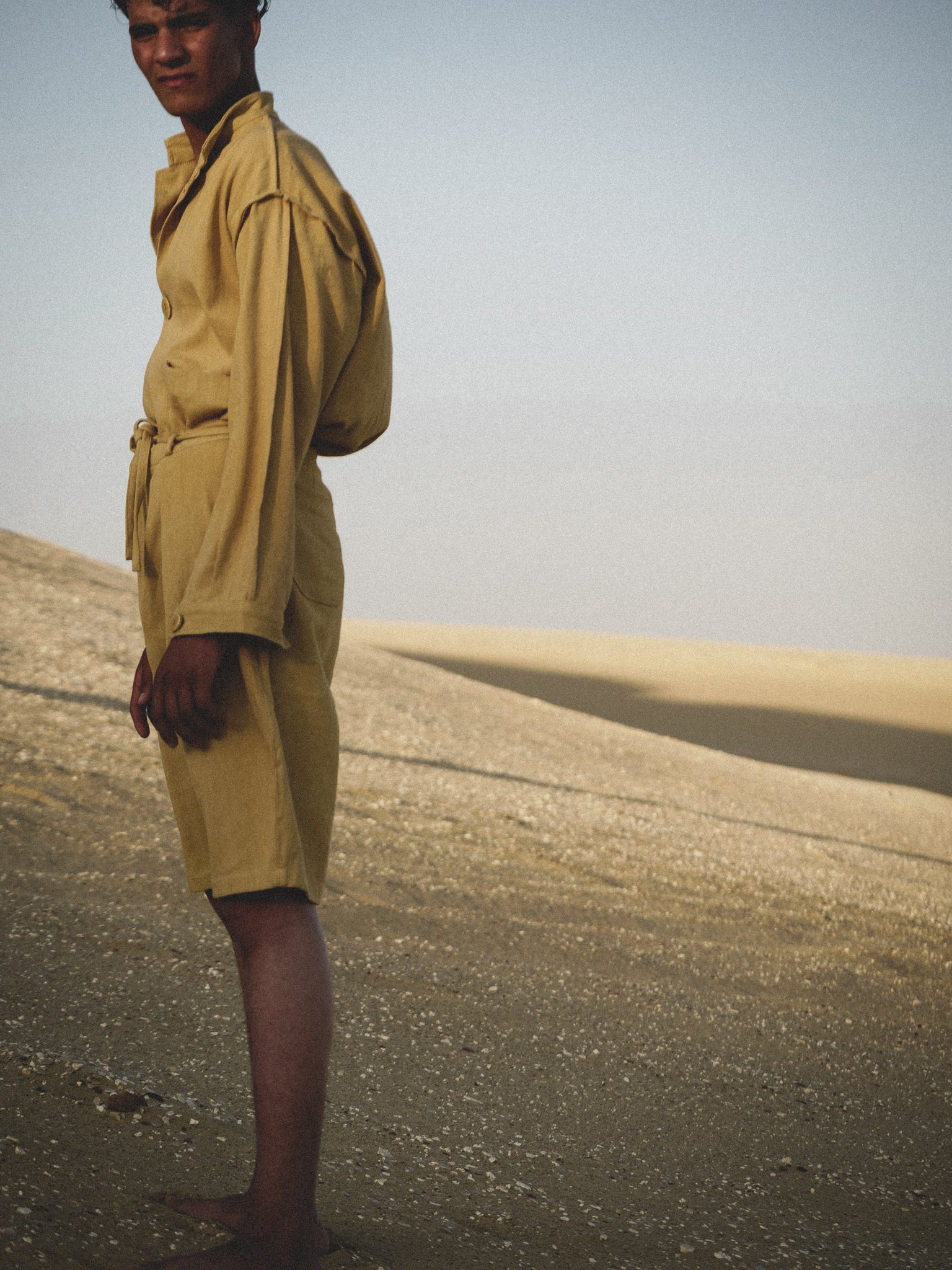 Person wearing a mustard outfit standing in a desert landscape
