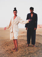 Two people in suits standing in a desert landscape with a plain background