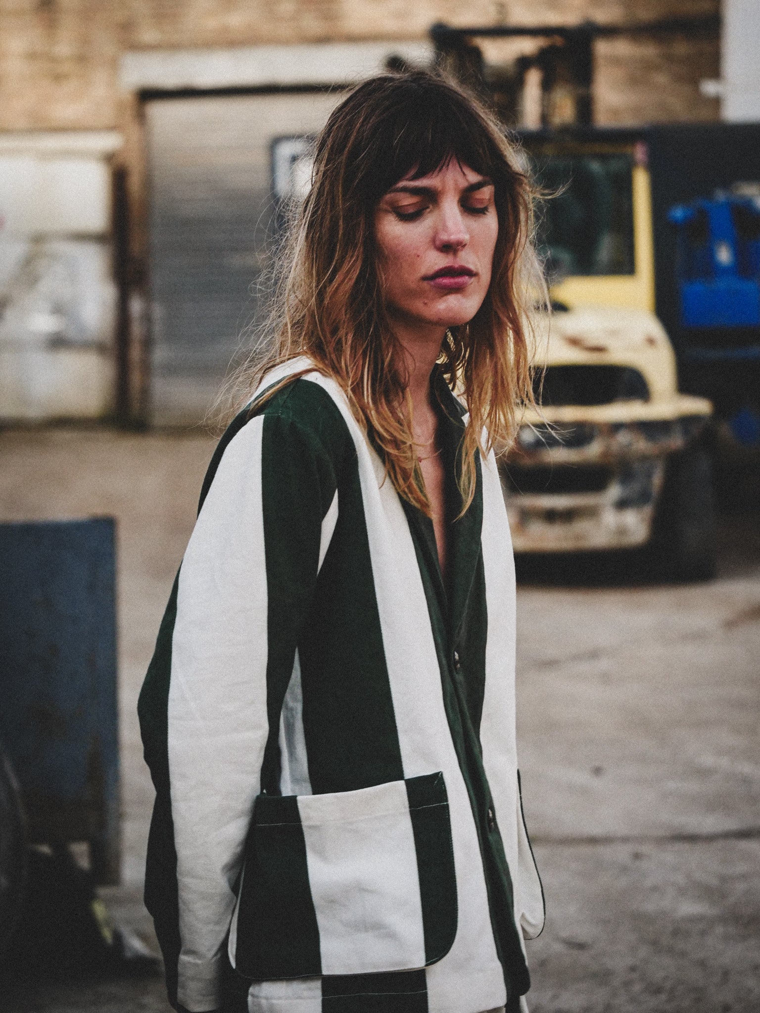 Woman wearing a green and white striped jacket in an industrial setting