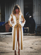 Woman wearing a mustard and white outfit standing in an industrial setting