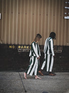 Two people wearing matching striped outfits walking on a street.