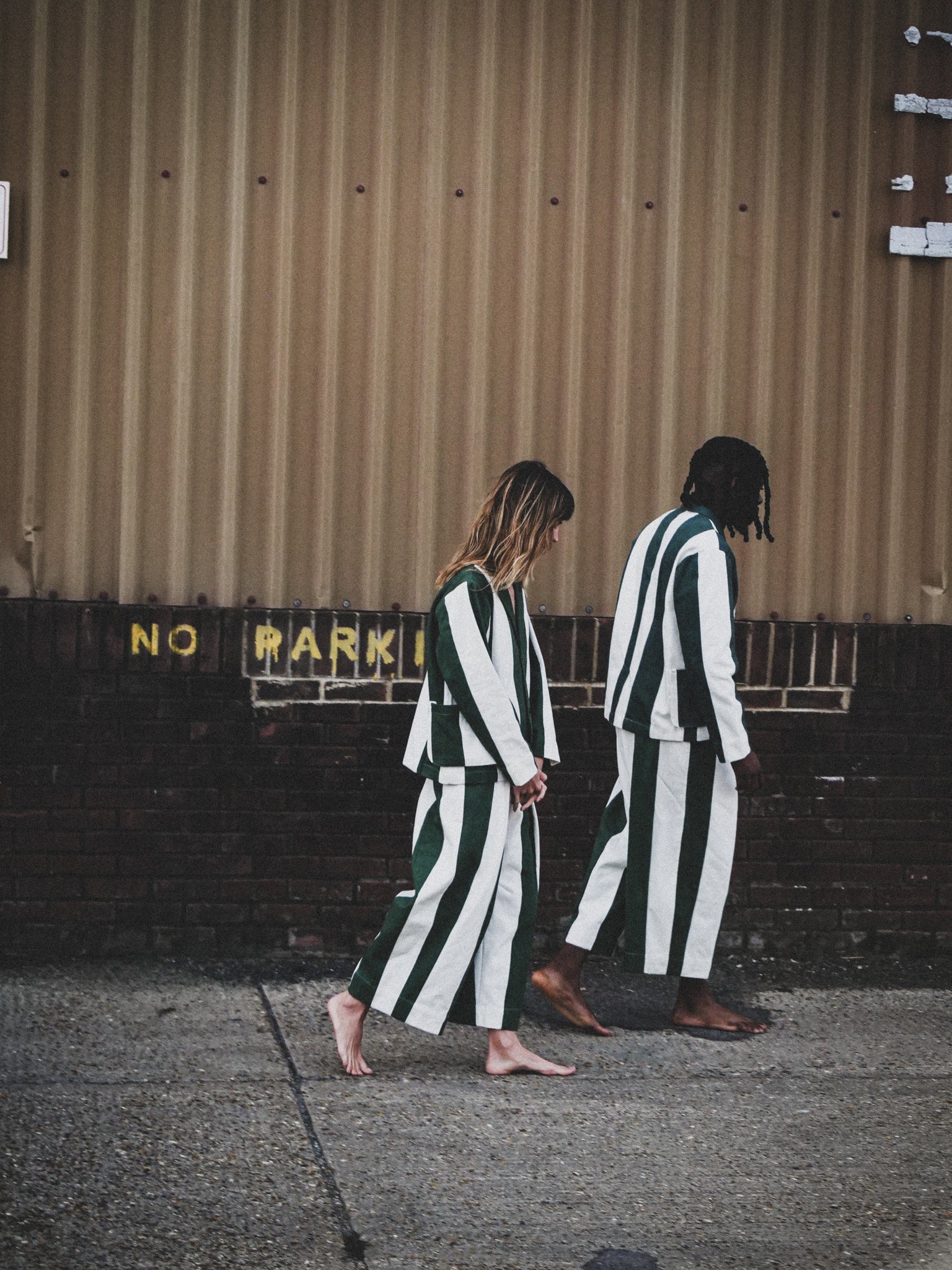 Two people wearing matching striped outfits walking on a street.