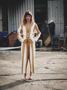 Woman in a mustard and white suit standing in an industrial setting