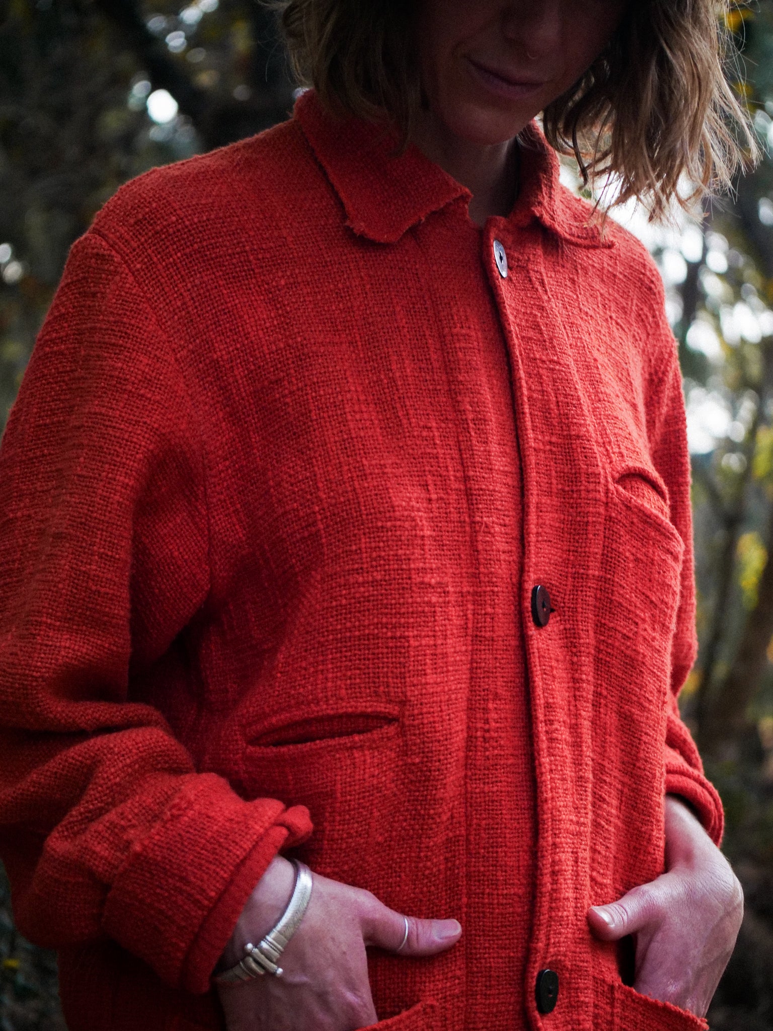 Woman wearing a red textured jacket with a blurred natural background