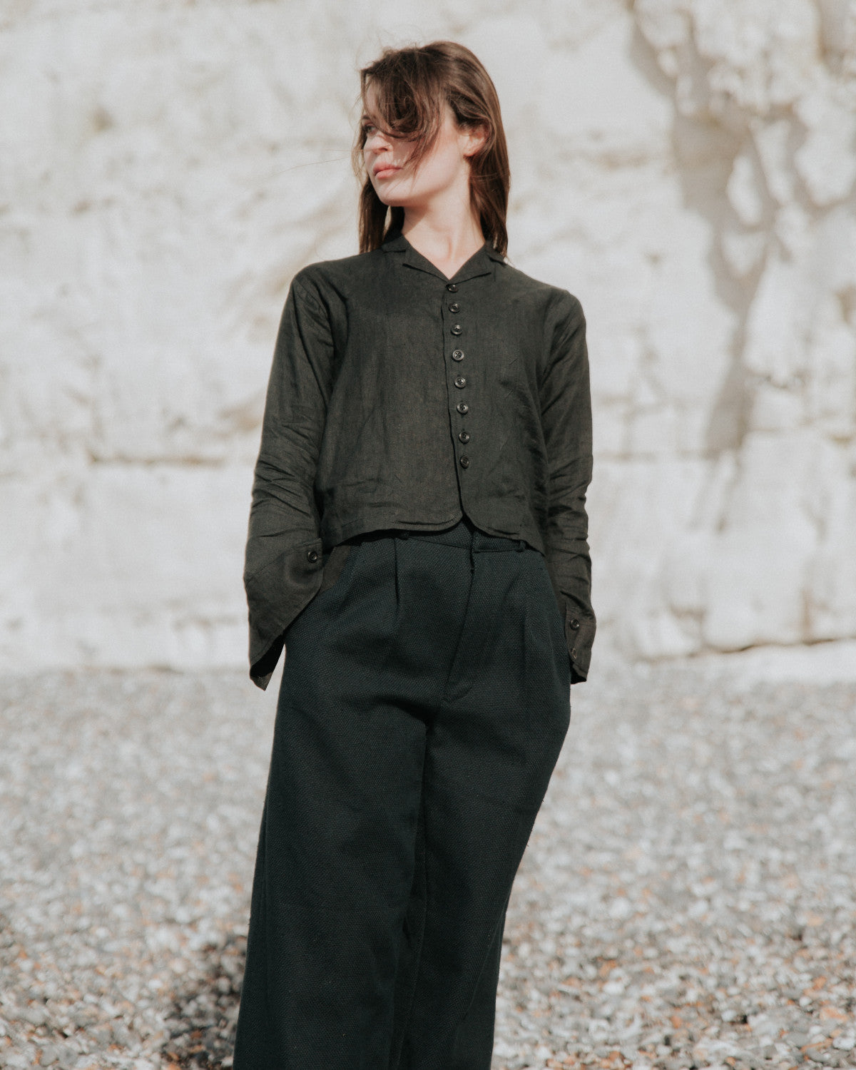 Person wearing a black shirt and pants against a textured wall.
