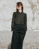 Person wearing a black shirt and pants against a textured wall.
